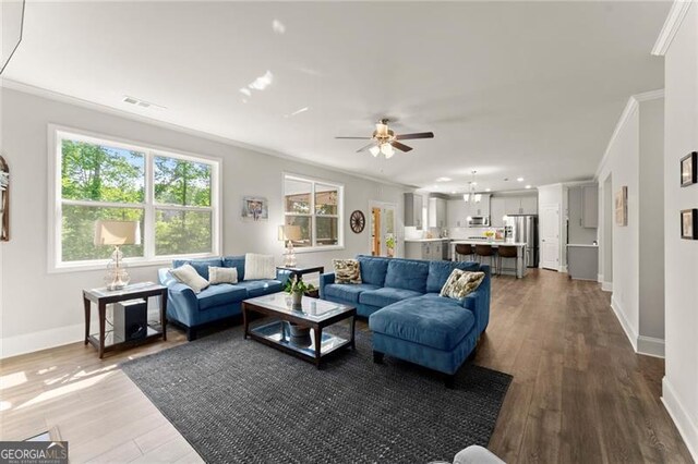 living room with ornamental molding, baseboards, dark wood finished floors, and a ceiling fan