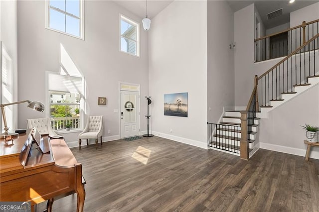 entryway with a high ceiling, wood finished floors, stairway, and baseboards
