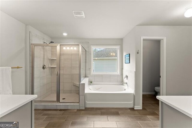 bathroom featuring vanity, a stall shower, toilet, wood tiled floors, and recessed lighting