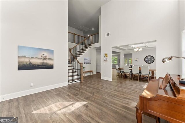 entrance foyer featuring a towering ceiling, stairway, a chandelier, wood finished floors, and baseboards