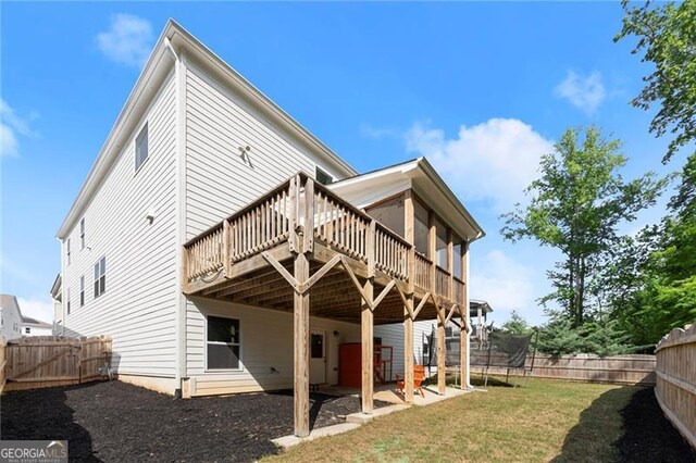 back of house featuring a wooden deck and a trampoline