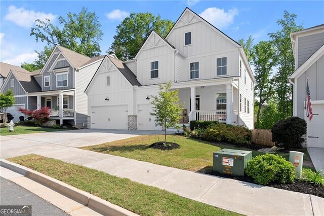 view of front facade featuring board and batten siding, concrete driveway, covered porch, and a front yard
