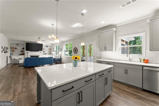 kitchen featuring stainless steel dishwasher, gray cabinetry, a ceiling fan, a fireplace, and ornamental molding
