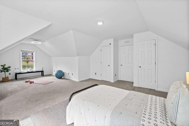 carpeted bedroom with lofted ceiling, baseboards, and multiple closets