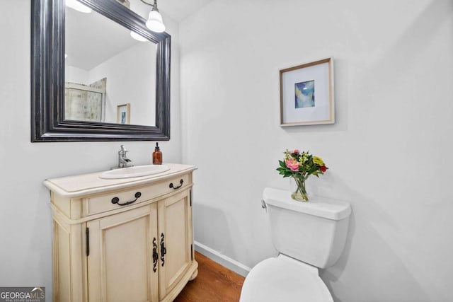 bathroom with toilet, wood finished floors, vanity, baseboards, and an enclosed shower