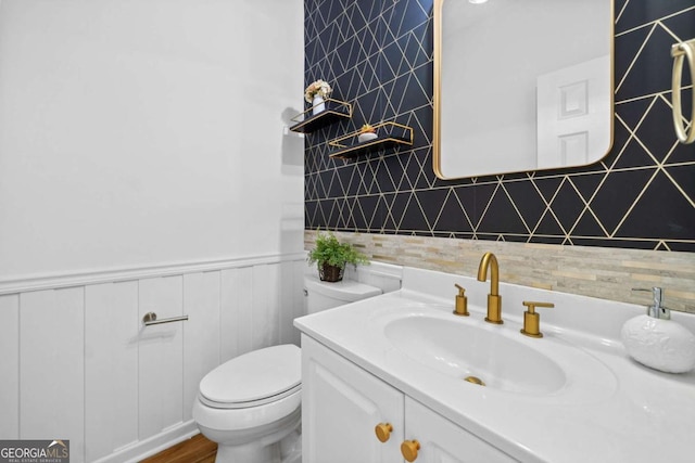 bathroom with toilet, vanity, backsplash, and wood finished floors