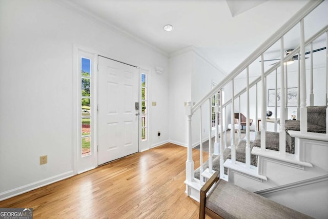 entryway featuring stairway, crown molding, wood finished floors, and baseboards