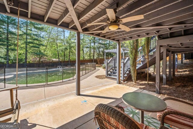 view of patio / terrace with stairs, a ceiling fan, a fenced backyard, and view of wooded area