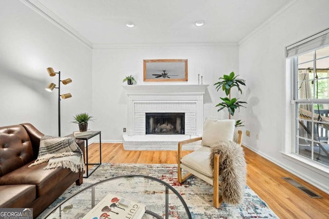living area featuring wood finished floors, ornamental molding, a fireplace, baseboards, and recessed lighting