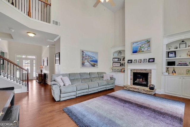 4100 Secret Shoals Way, Buford, GA 30518 - living area featuring a high ceiling, built in shelves, wood finished floors, ceiling fan, and a fireplace
