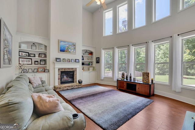 4100 Secret Shoals Way, Buford, GA 30518 - living room featuring a high ceiling, built in features, a fireplace, ceiling fan, and wood finished floors