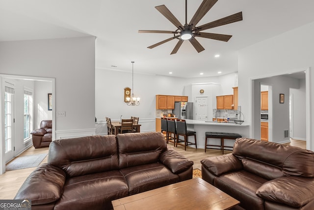 living room featuring light wood finished floors, a ceiling fan, a chandelier, and recessed lighting
