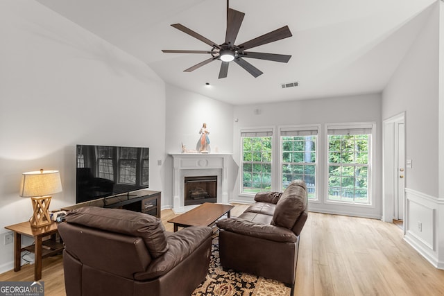living area with light wood finished floors, a premium fireplace, a ceiling fan, and lofted ceiling