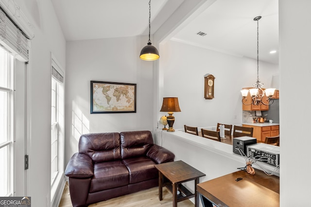 living area featuring a chandelier, light wood finished floors, and beamed ceiling
