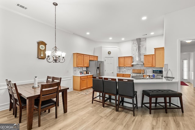 kitchen featuring wall chimney exhaust hood, a breakfast bar, a peninsula, backsplash, and recessed lighting