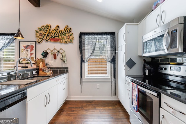 kitchen featuring appliances with stainless steel finishes, a sink, lofted ceiling, dark wood-style flooring, and white cabinets