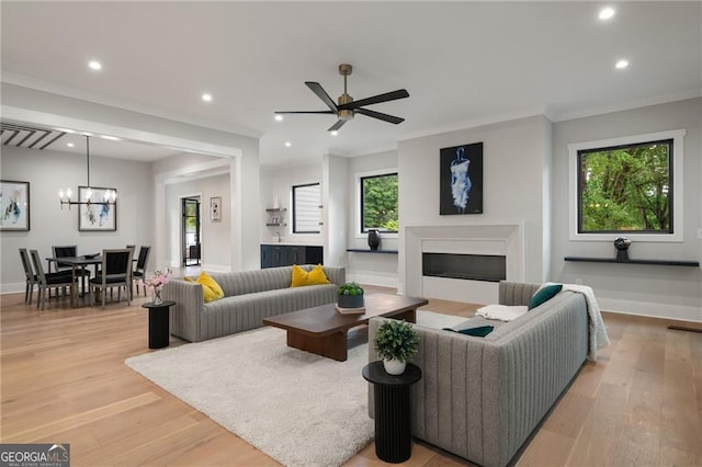 living area featuring a fireplace, ornamental molding, recessed lighting, baseboards, and light wood-style flooring