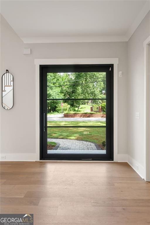 doorway to outside with healthy amount of natural light, wood finished floors, crown molding, and baseboards