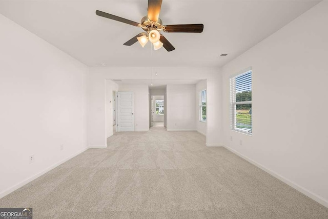 spare room with baseboards, ceiling fan, and light carpet