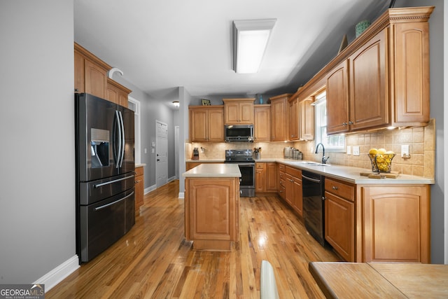 kitchen with stainless steel appliances, a sink, a center island, light countertops, and decorative backsplash