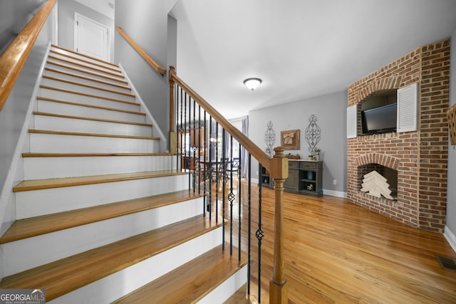 stairs featuring wood finished floors and a fireplace