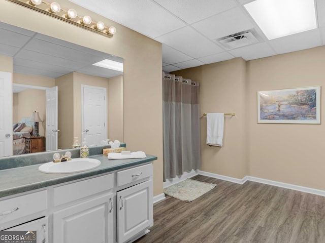 full bath with a drop ceiling, wood finished floors, vanity, baseboards, and curtained shower
