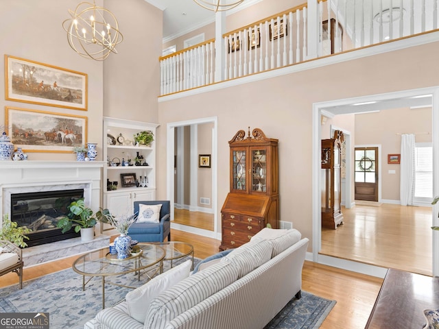 219 Eagles Landing Way, Mcdonough, GA 30253 - living room featuring a chandelier, light wood-style flooring, built in features, a towering ceiling, and a premium fireplace