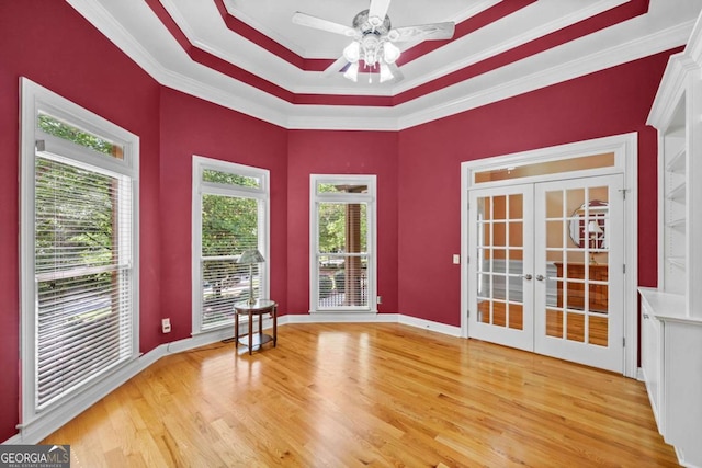spare room featuring crown molding, wood finished floors, french doors, a ceiling fan, and a raised ceiling