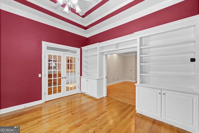 unfurnished room with french doors, light wood-type flooring, ceiling fan, crown molding, and baseboards