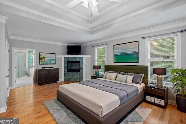 bedroom with light wood-style flooring, multiple windows, ornamental molding, baseboards, and a raised ceiling