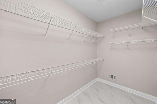 spacious closet featuring marble finish floors