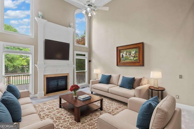carpeted living room featuring a high ceiling, a ceiling fan, a fireplace with flush hearth, and baseboards