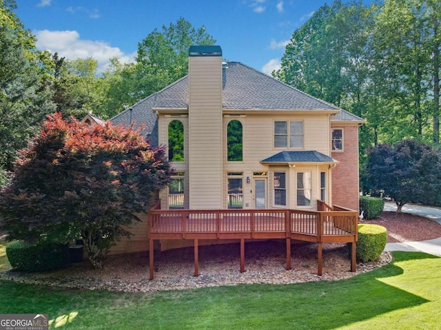 back of property featuring a wooden deck, a yard, a chimney, and roof with shingles