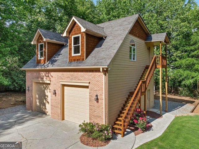 view of property exterior with stairs, a garage, roof with shingles, brick siding, and view of wooded area