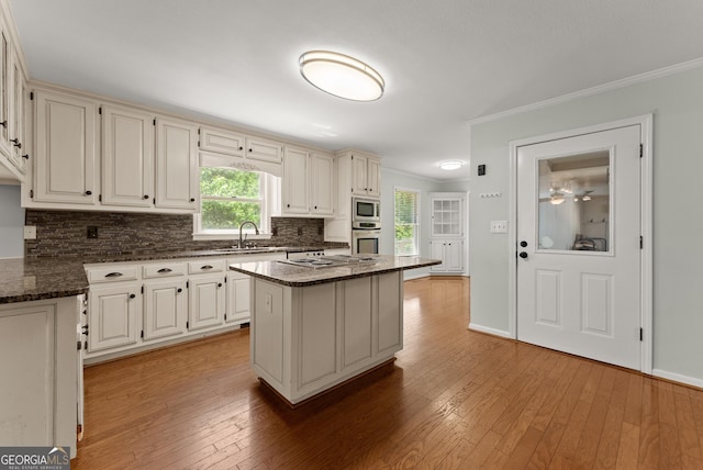 5103 Whispering Pines Dr, Gainesville, GA 30504 - kitchen featuring appliances with stainless steel finishes, backsplash, crown molding, dark stone counters, and light wood-type flooring