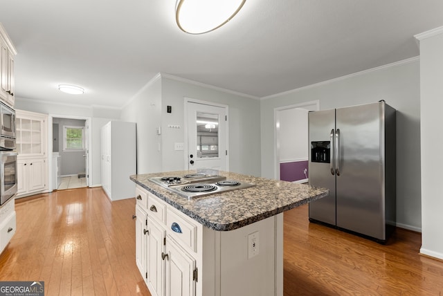 kitchen featuring appliances with stainless steel finishes, light wood finished floors, crown molding, a kitchen island, and white cabinetry