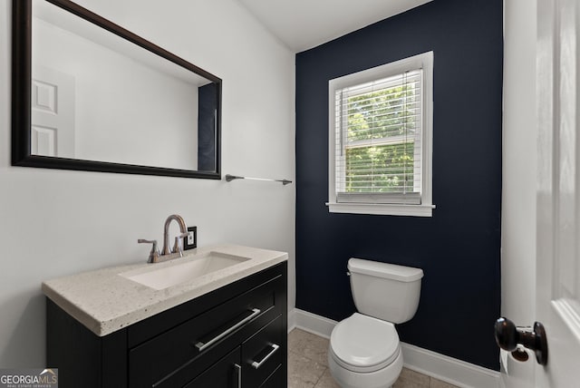 bathroom with toilet, vanity, and baseboards