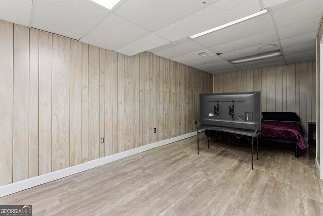 sitting room featuring a drop ceiling, wood finished floors, wood walls, and baseboards