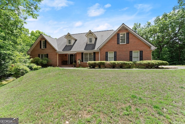 view of front of home with brick siding, a front lawn, a porch, and roof with shingles