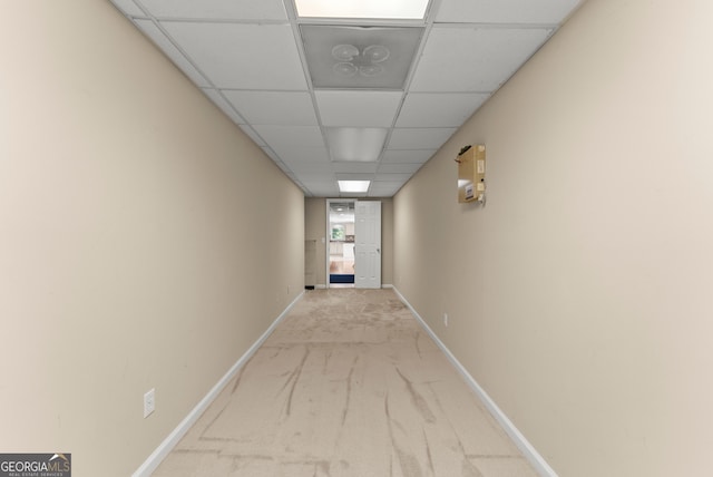 hallway with a paneled ceiling, carpet, and baseboards