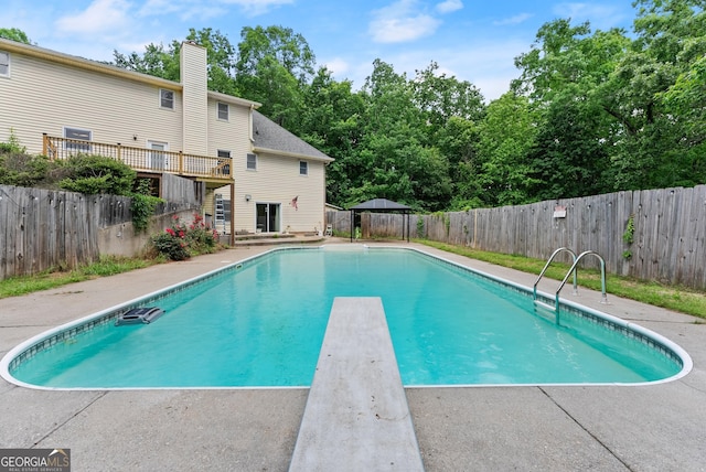 view of pool with a fenced backyard and a diving board