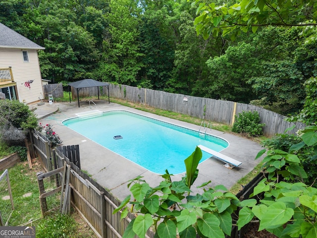 view of pool with a gazebo, a fenced backyard, a diving board, and a patio area