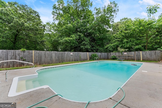 view of pool with a patio, a fenced backyard, and a diving board