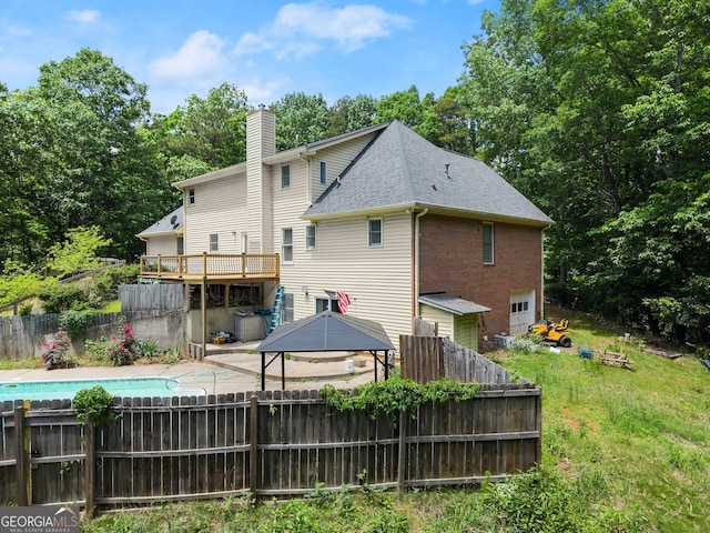 back of property featuring a chimney, a fenced backyard, a gazebo, an attached garage, and a deck