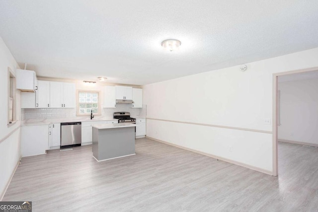 315 Henson Cir, Carrollton, GA 30117 - kitchen featuring appliances with stainless steel finishes, light wood-type flooring, under cabinet range hood, tasteful backsplash, and light countertops