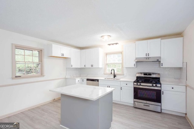315 Henson Cir, Carrollton, GA 30117 - kitchen with stainless steel appliances, under cabinet range hood, a sink, backsplash, and light wood-type flooring