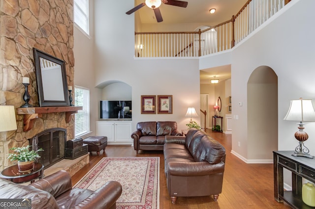 5960 Bridge Stone Ct, Cumming, GA 30028 - living room with a fireplace, a ceiling fan, a high ceiling, and wood finished floors