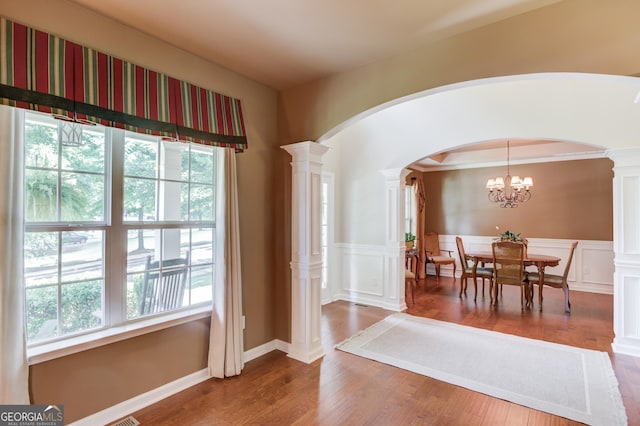 5960 Bridge Stone Ct, Cumming, GA 30028 - dining area featuring arched walkways, decorative columns, wood finished floors, and wainscoting
