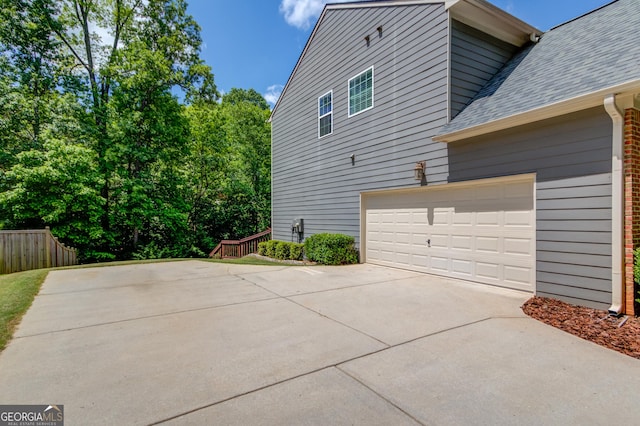 5960 Bridge Stone Ct, Cumming, GA 30028 - view of property exterior with concrete driveway, roof with shingles, fence, and a garage