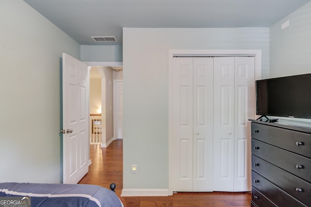 5960 Bridge Stone Ct, Cumming, GA 30028 - bedroom featuring wood finished floors, a closet, arched walkways, and baseboards